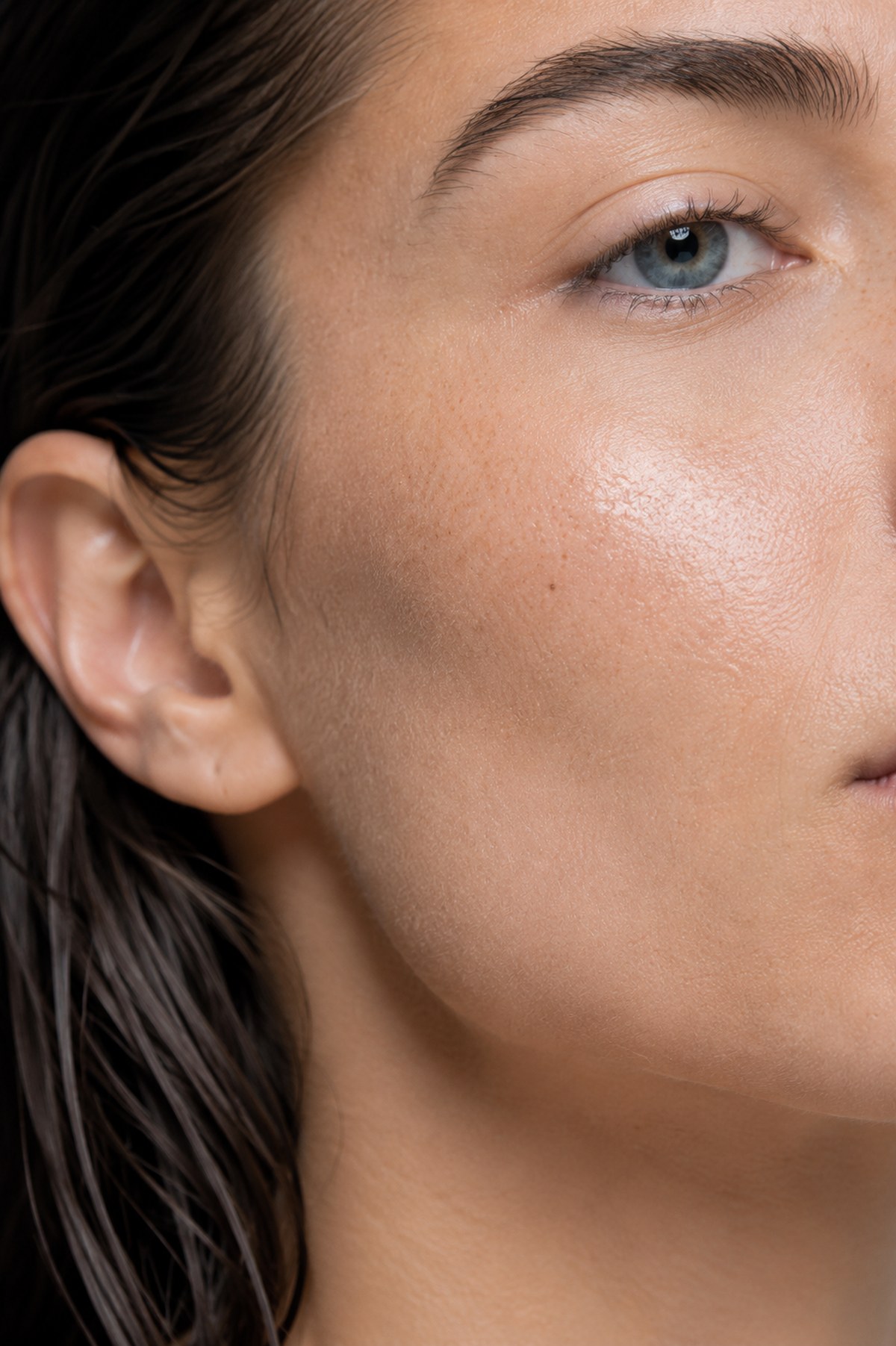 Skin close — cheekbone and jaw, product sheen, unretouched texture